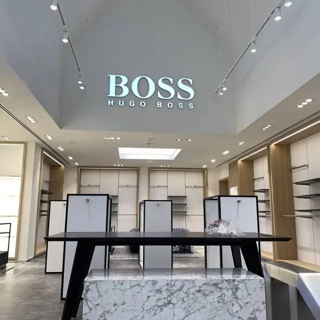 Hugo Boss store at Bicester Village: double-height ceiling with BOSS sign, track lighting and linear slot diffusers