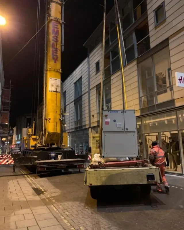Night crane lift in York: Daikin replacement chiller on a trailer beside an Emsley Liebherr crane, operative in hi-vis