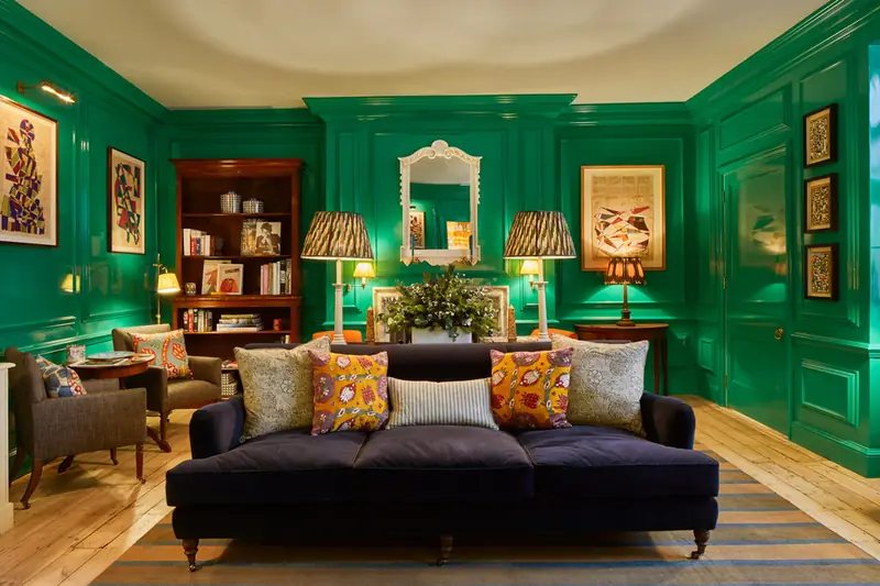 Emerald lacquered lounge at Hackett Savile Row with navy velvet sofa, patterned cushions and table lamps