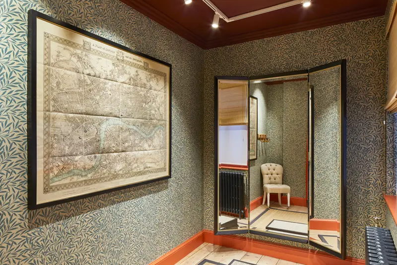 Hackett Savile Row fitting room with willow-pattern wallpaper, antique London map, tri-fold mirror and column radiator