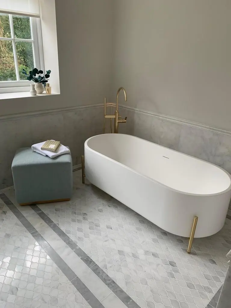 Freestanding white bath with brushed-brass floor-standing filler on marble mosaic floor, Hampstead residence
