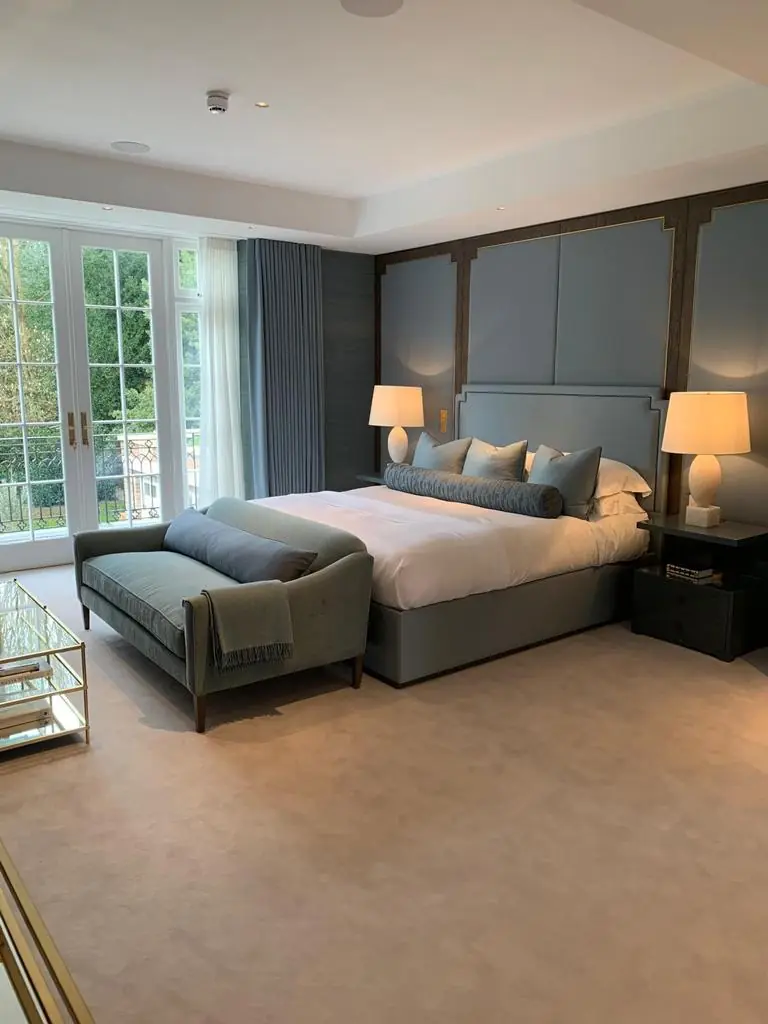 Hampstead residence master bedroom with blue-grey panelled headboard wall and French doors to a balcony
