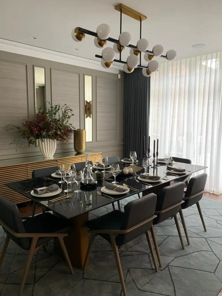 Hampstead residence dining room with black marble table laid for eight under a brass globe chandelier