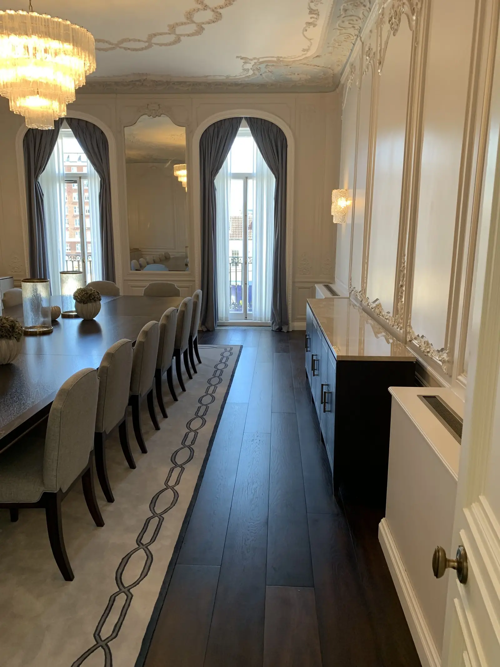 Mayfair residence dining room toward arched windows, with perimeter enclosures and linear grilles concealing the heating and cooling units